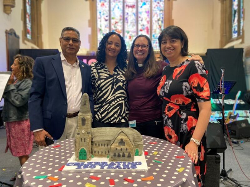 Seema Malhotra MP and members of the church community pose in front of a cake shaped like Hope Church