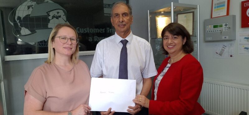 Seema Malhotra MP, Ray Singh of Russell Finex and Sarah Smith hold an envelope together
